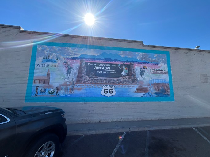 Mural reading “10,000 nice people welcome you to Winslow” painted on a brick building in Winslow, Arizona