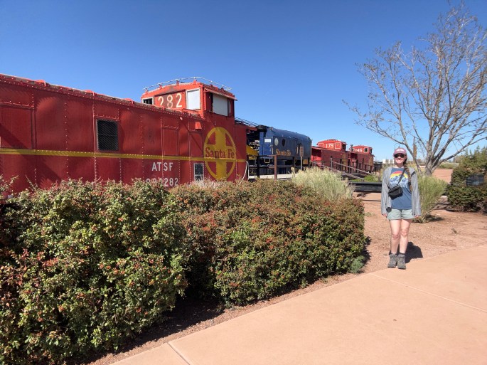 Traveler standing in front of a vintage Santa Fe locomotive on display in Winslow, Arizona