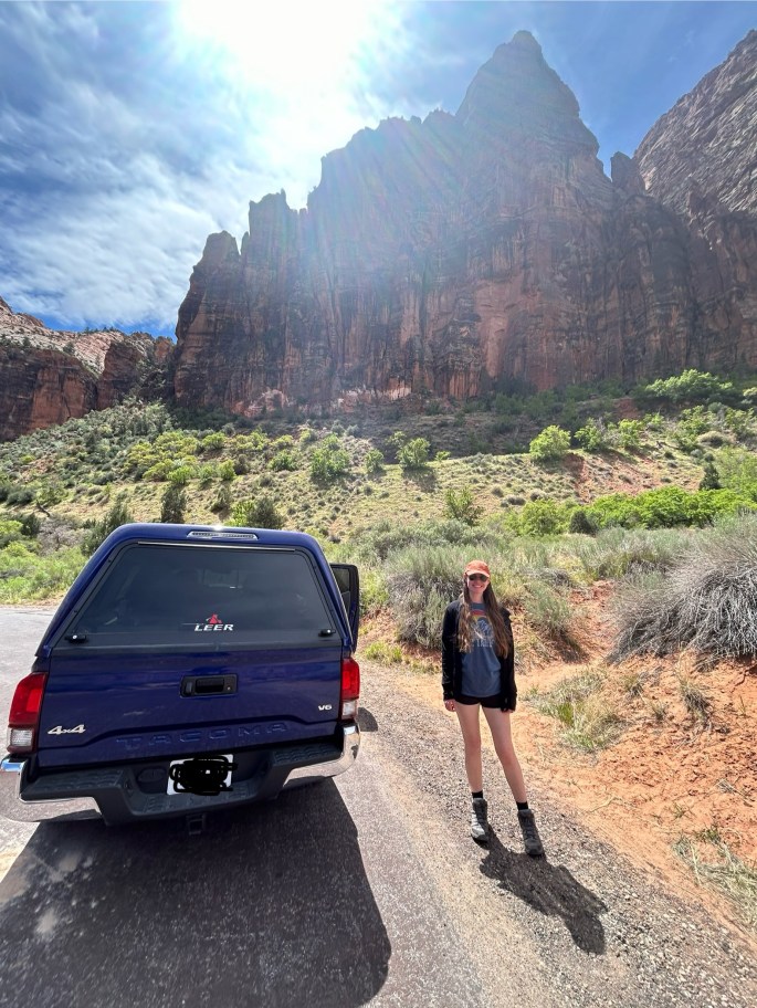 Traveler with Toyota Tacoma in front of Zion red rock cliffs
